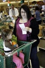 AP - Karen Wilmes of Hopkinton, R.I. checks out her savings while her daughter, Allison, waits, during a shopping trip ...
